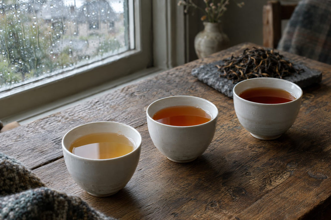 Three cups of Ceylon tea showing different strengths from golden to amber on an oak table
