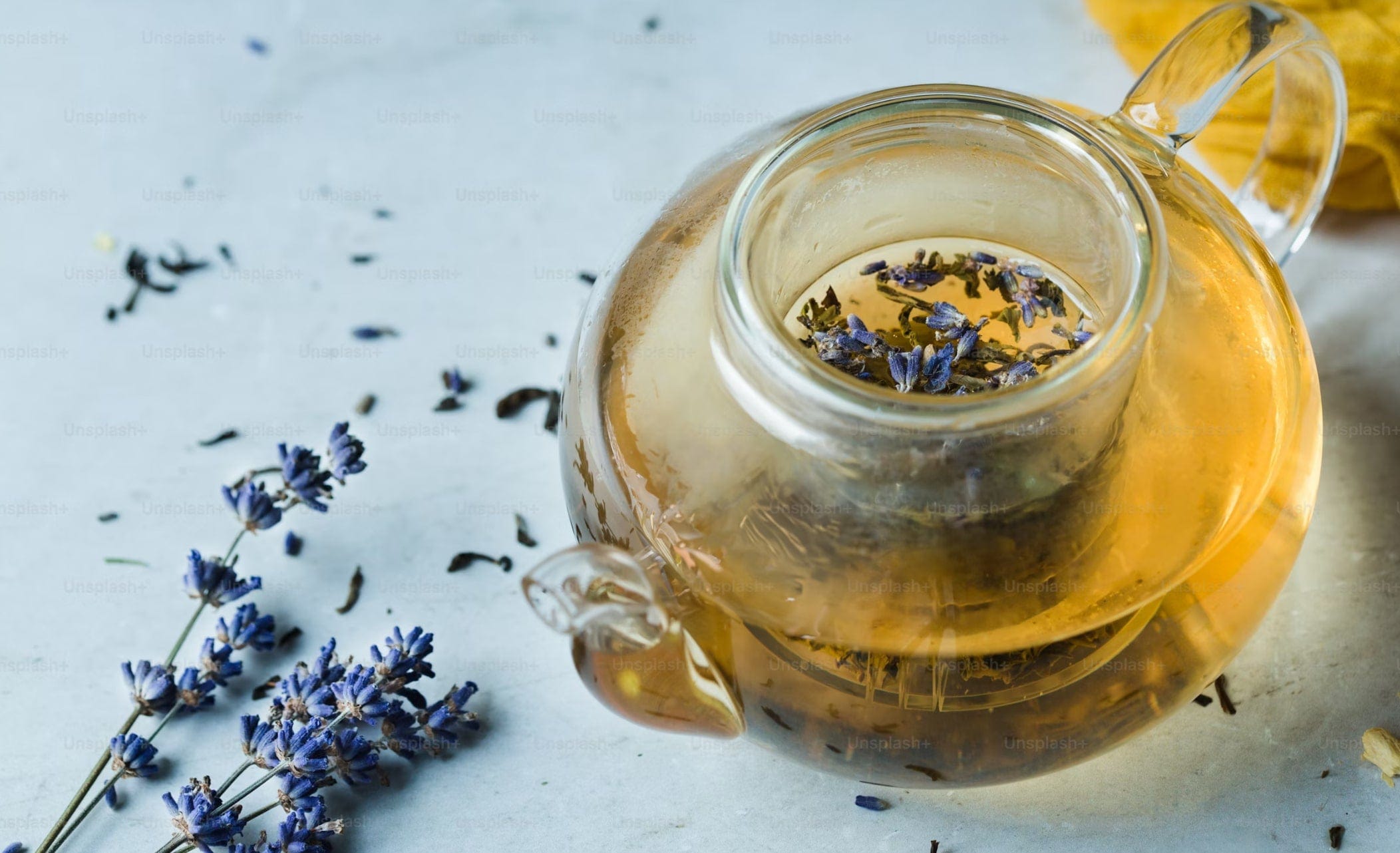 Clear glass teapot with lavender flowers on a light background
