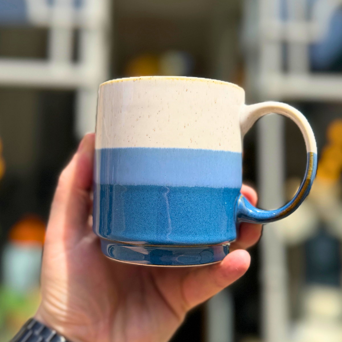 Blue Elements mug held in a hand, showing the pale upper section and blue glaze bands