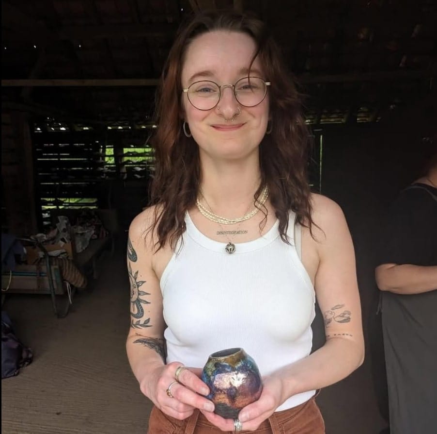 Woman holding a small ceramic vase indoors