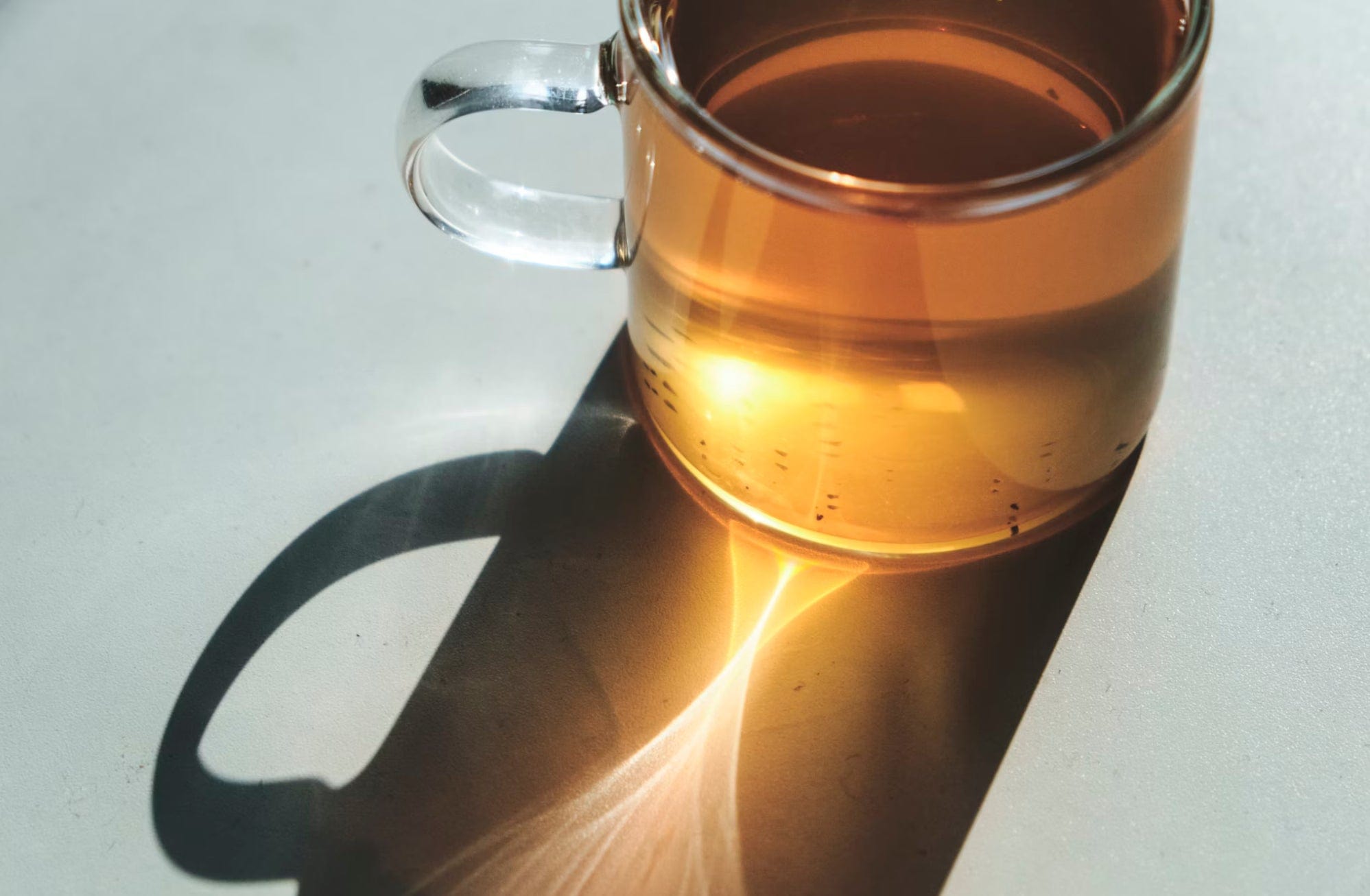 Clear glass mug filled with tea on a white surface