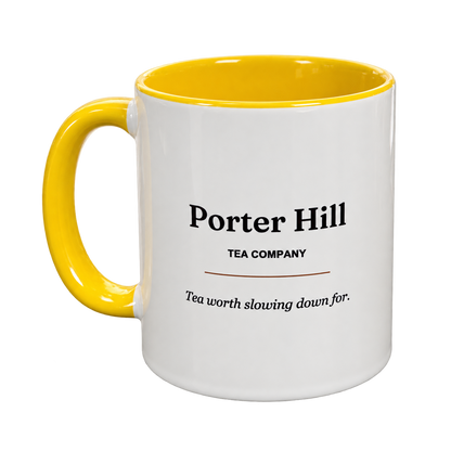 White Porter Hill tea mug with yellow handle and interior, showing the Porter Hill logo and Tea worth slowing down for slogan