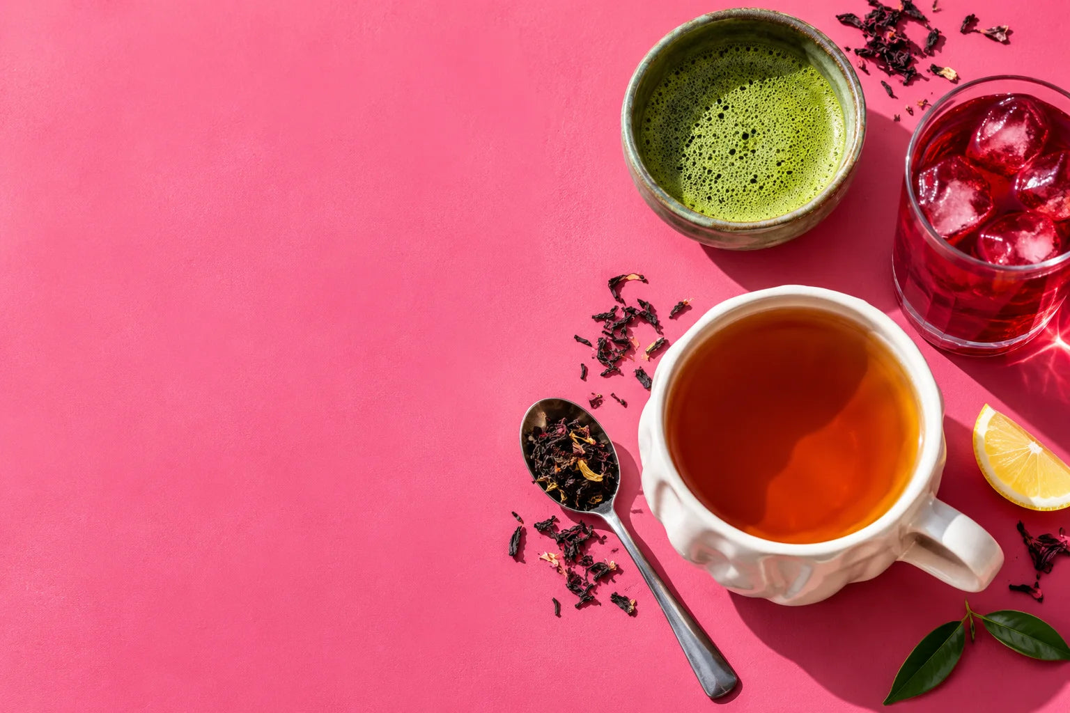 Three colourful cups of loose leaf tea with scattered tea leaves