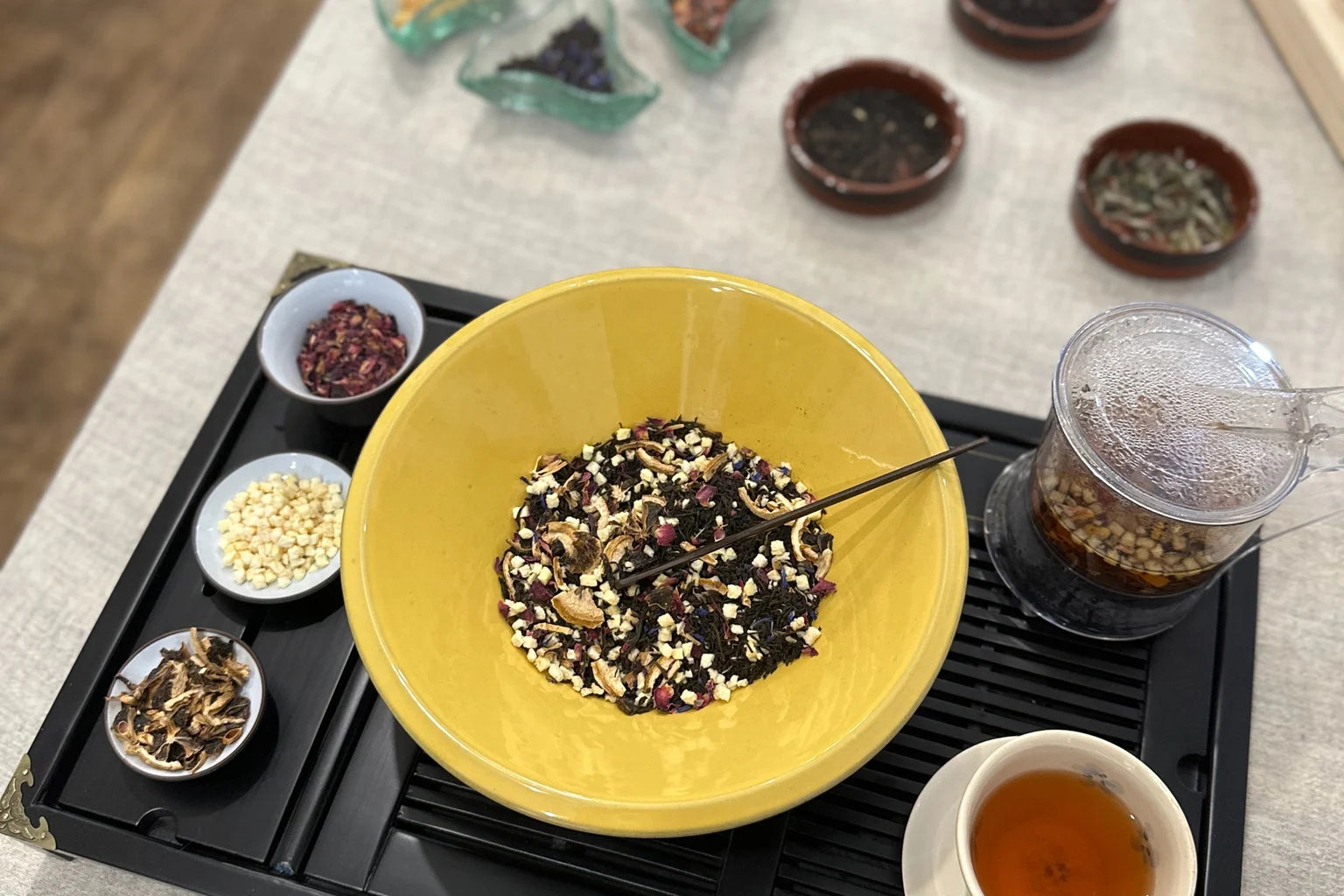 Three colourful cups of loose leaf tea with scattered tea leaves